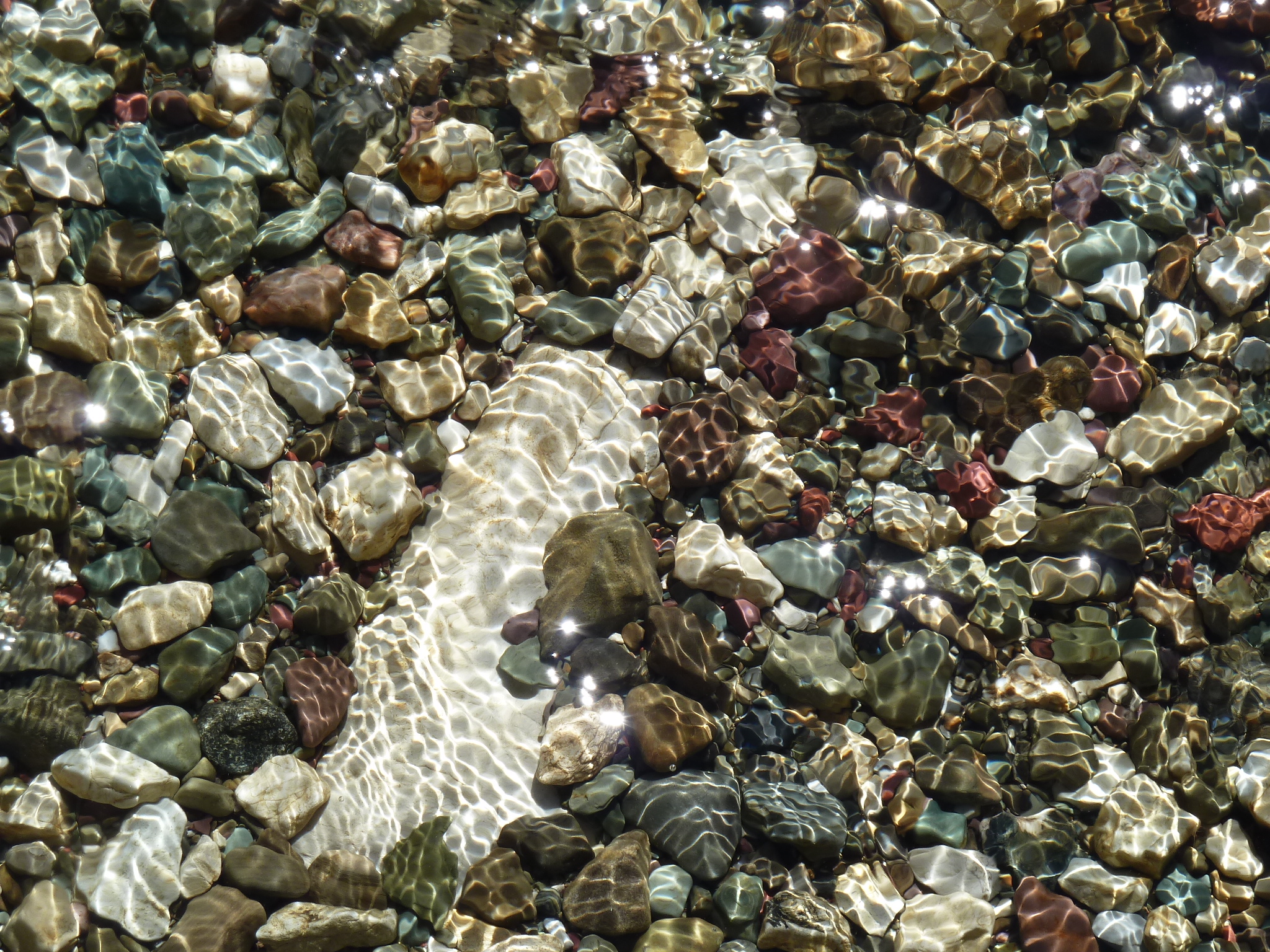 Gravel and stones underneath the water in a stream.